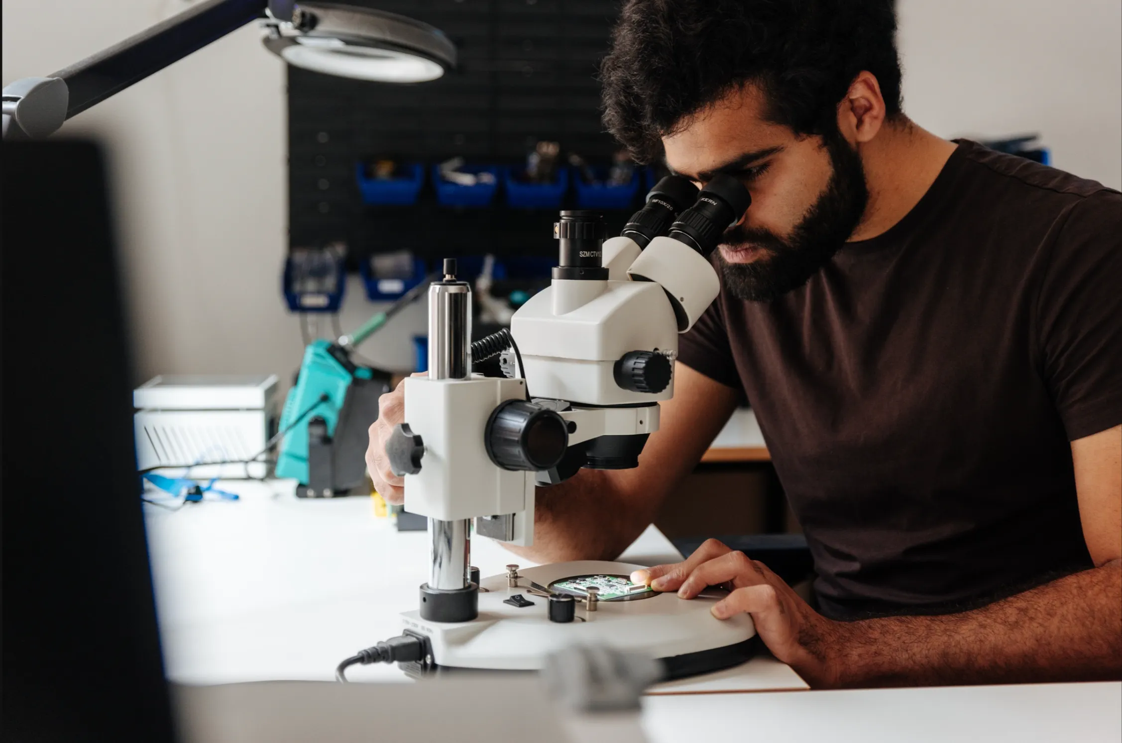 A Better Devices engineer inspecting a board under a stereo microscope
